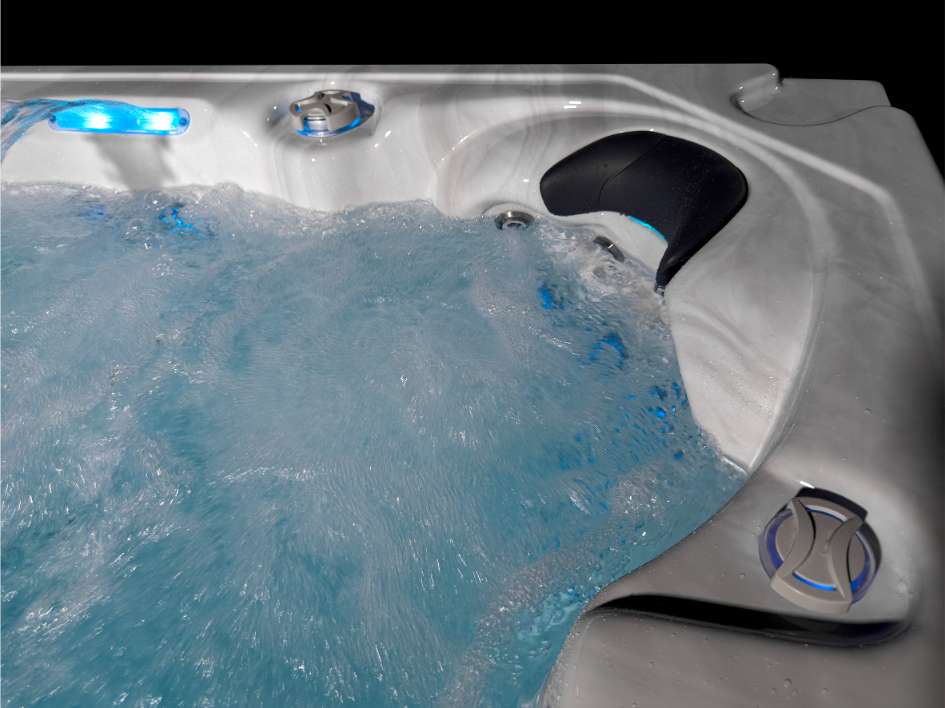 Oasis hot tub lounger seat with hydrotherapy jets running and blue LED waterfall feature.