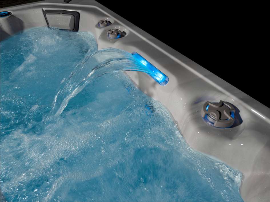 Close-up of the Oasis hot tub waterfall feature with illuminated blue water flow.