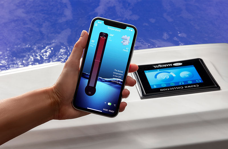 Hand holding a smartphone showing the ControlMySpa temperature control app next to a spa display panel.