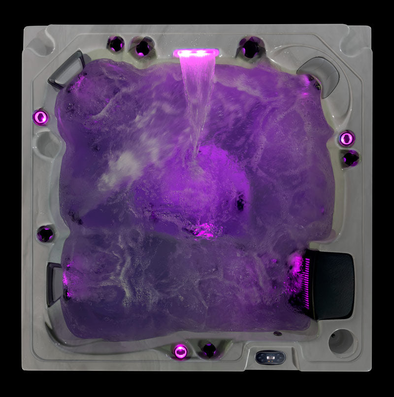 Fjord hot tub with purple LED lighting and waterfall feature viewed from above.