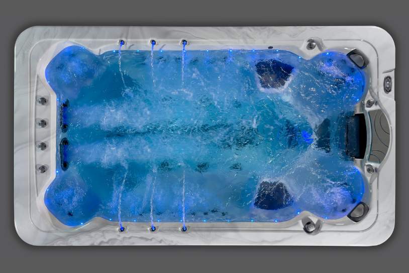 Top-down view of the Fossa-3B swim spa with bright blue LED lighting and active water jets.