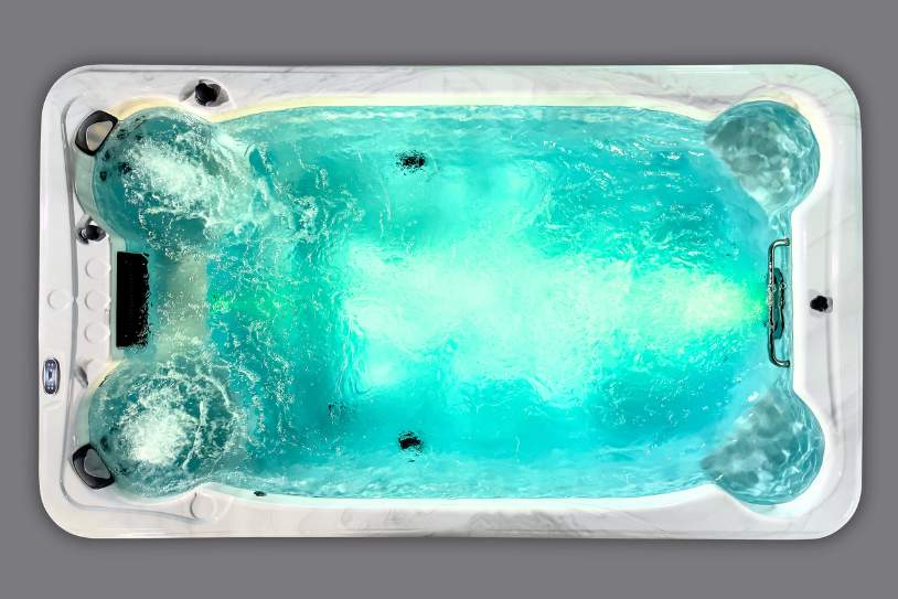 Fossa PP overhead view of a swim spa with turquoise LED lighting and active water jets.
