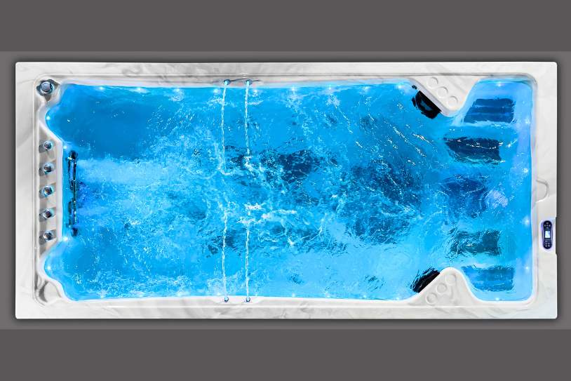 Swim spa photographed from above showing blue illuminated turbulent water.