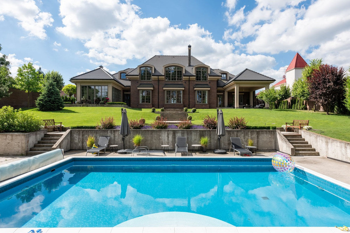Backyard in-ground swimming pool with a rolled pool cover, ready for closing with pool closing chemicals