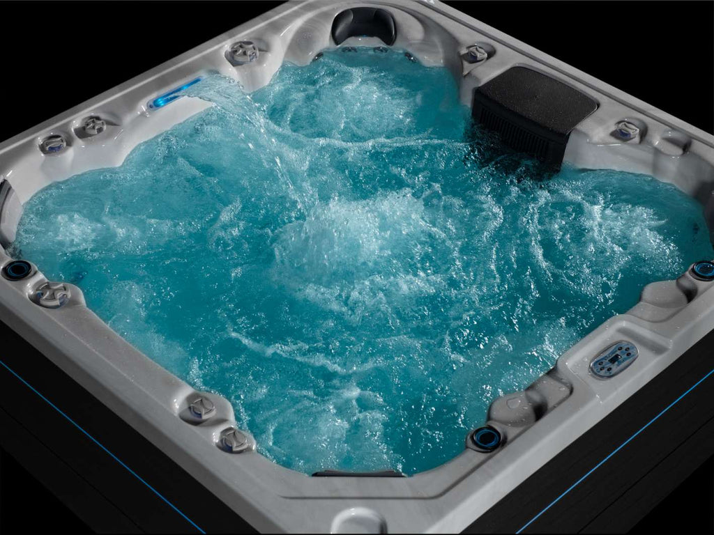 Angled view of the Oasis hot tub with all jets running and illuminated water features.