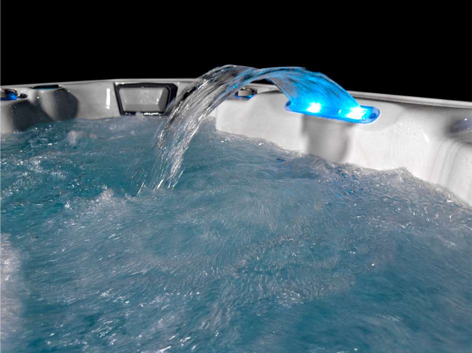 Oasis hot tub waterfall feature with illuminated blue LED lighting and bubbling water.