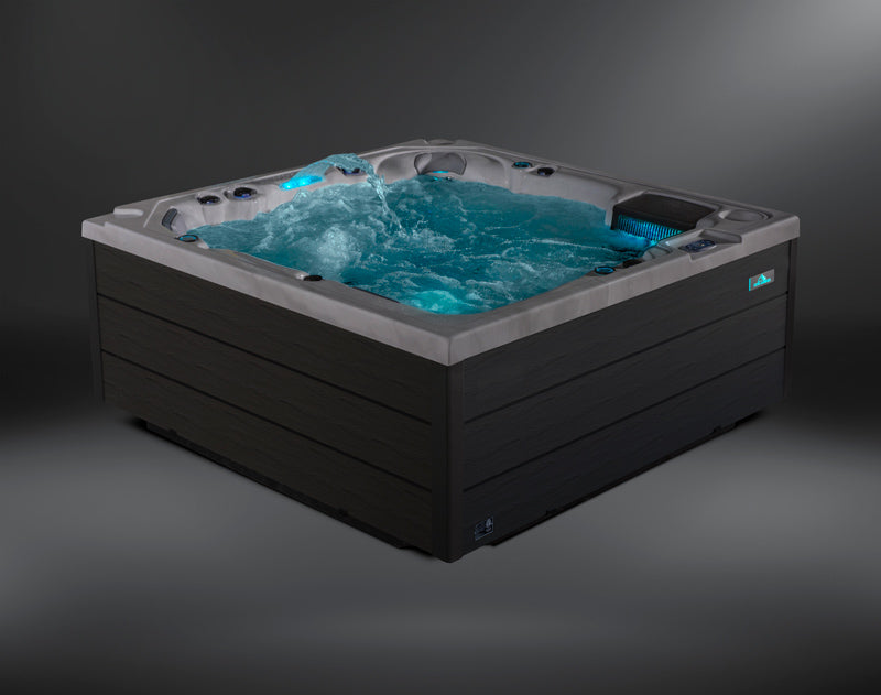Corner view of the Fjord hot tub with illuminated waterfall and active jets.