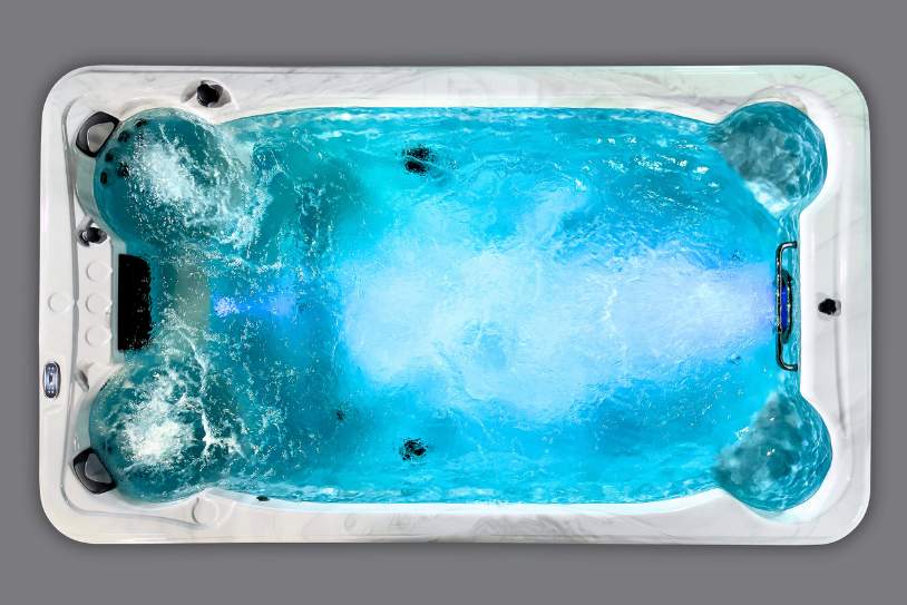 Fossa PP overhead view of a brightly lit blue swim spa with active jets creating bubbling water.