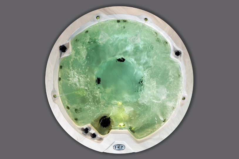 Top-down view of the Cyclone 1 hot tub with soft green lighting and swirling water.