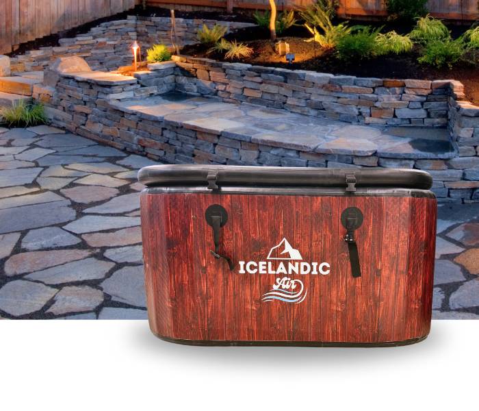 Icelandic Air inflatable tub displayed outdoors on a stone patio with landscaping in the background.