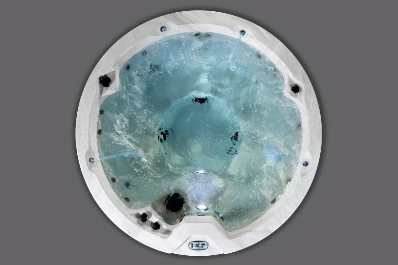 Overhead view of the Cyclone 1 hot tub with water circulation and light blue illumination across the interior.