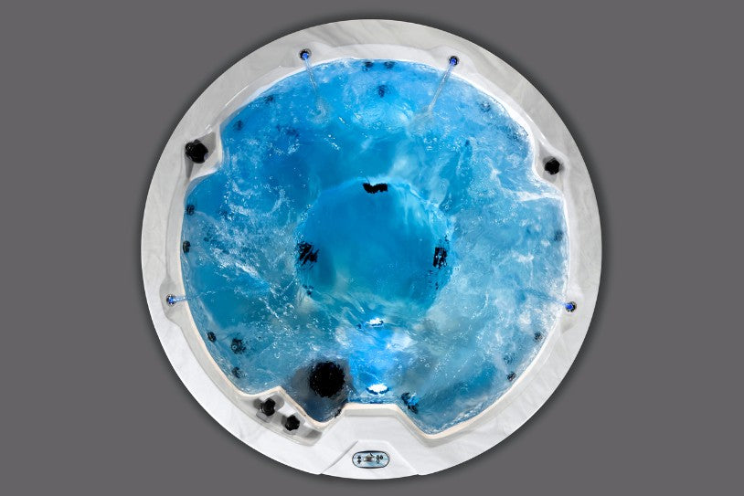 Bright blue-lit overhead view of the Icelandic Cyclone 1 hot tub with jets and fountains running.