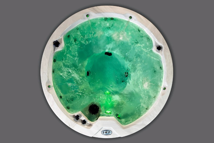 Overhead view of the Cyclone 1 hot tub illuminated with deeper green LED lighting while jets run.