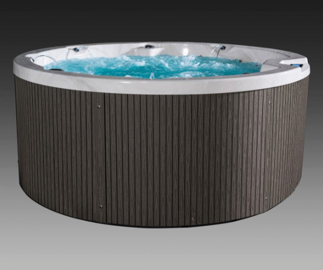 Round Icelandic Cyclone 3 hot tub with bubbling blue water and gray exterior paneling.