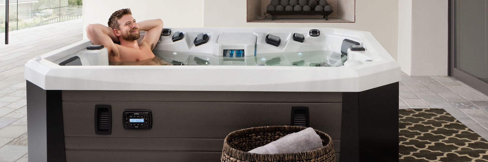 Man relaxing in a Vector21 Series V65L hot tub on a modern patio surrounded by clean architectural design.