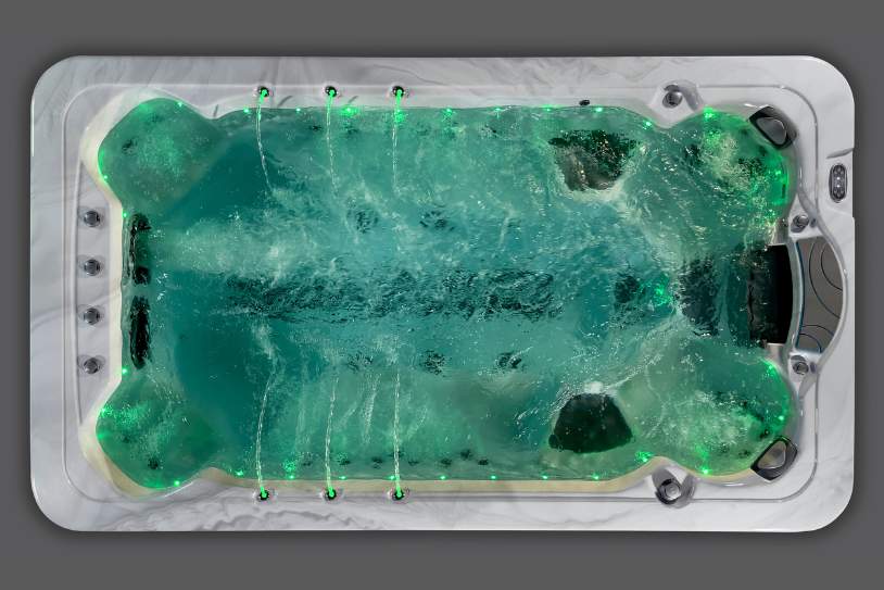 Overhead view of the Fossa-3B swim spa illuminated with green LED lighting and active jets.