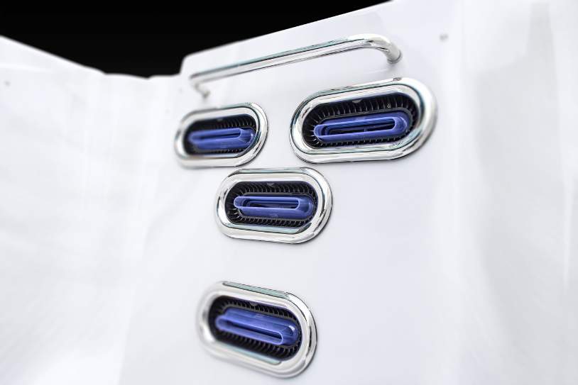 Close-up view of directional swim spa jets with chrome trim and blue inserts.