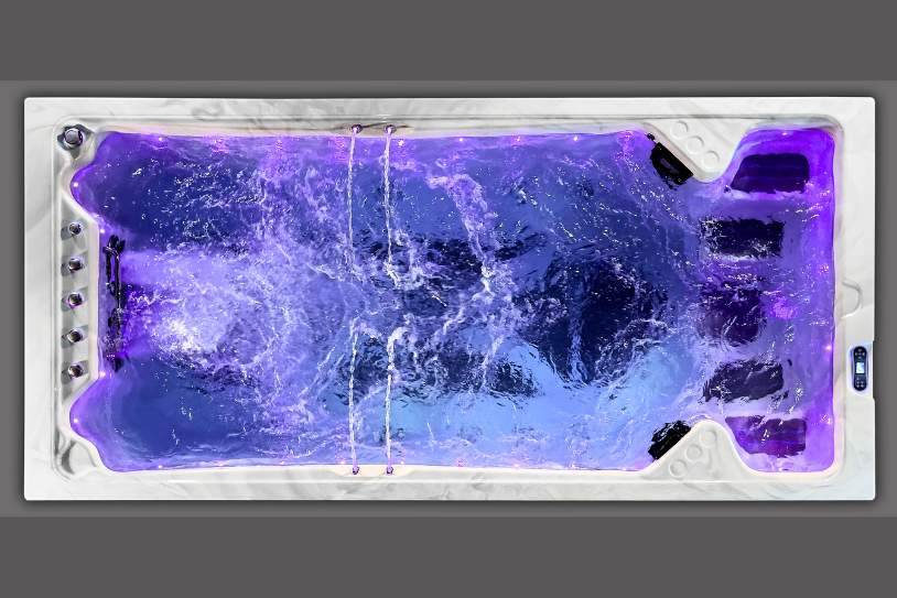 Top view of a swim spa with purple LED lighting and swirling water motion.