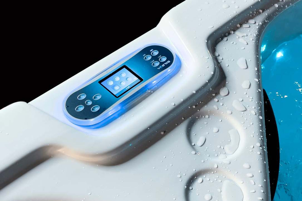 Close-up of the Triathlon swim spa digital control panel with illuminated buttons and water droplets.
