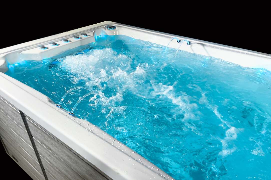 Triathlon 3-in-1 swim spa swim zone with strong water jets and illuminated blue water.